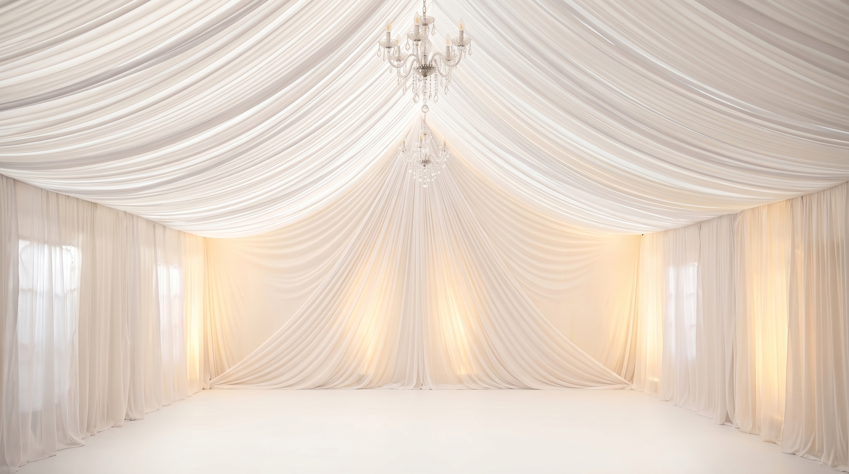 Tent draping with chandelier lighting inside an outdoor event tent
